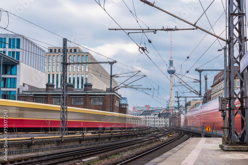 Trains in blur are leaving and approaching the station of Berlin Friedrichstrasse on a cool spring day. Typical houses and TV tower visible in the backgroubd. Train transport in germany, punctuality