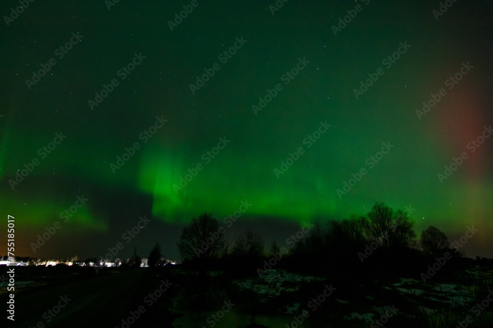 The Northern Lights over the city . The Aurora borealis in the night starry sky in winter.