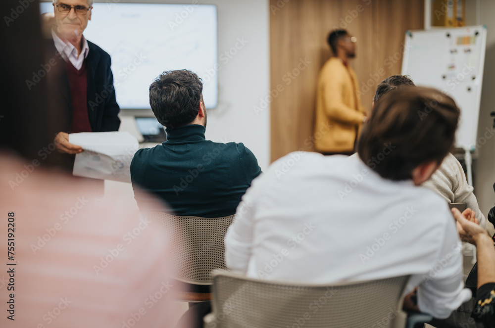 Fototapeta premium Focused group of professionals attending a business meeting with a speaker presenting. The setting is a contemporary office environment.