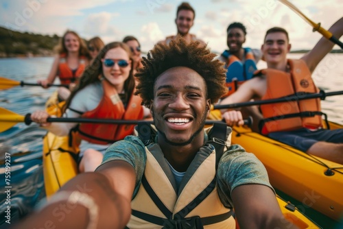 A young man with a captivating smile takes a selfie with a group of friends on a kayaking excursion, sharing the joy of their collective adventure. © Maria