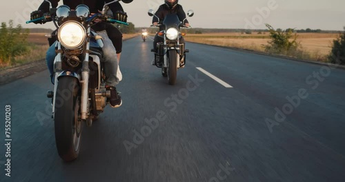 Bikers drive on the highway, close-up steering wheel. Other motorcyclists can be seen in the background.