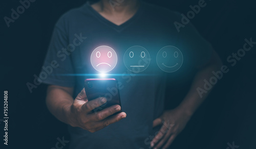 Customer experience dissatisfied concept, Businessman holding smartphone with sadness emotion face on screen, unhappy, Bad review, Low rating, Dissatisfied with products and services. photo