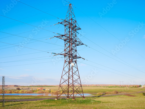 Metal power tower with high-voltage cables against the green field and the blue sky. The concept of energy, Energy transmission, the country's energy sector.