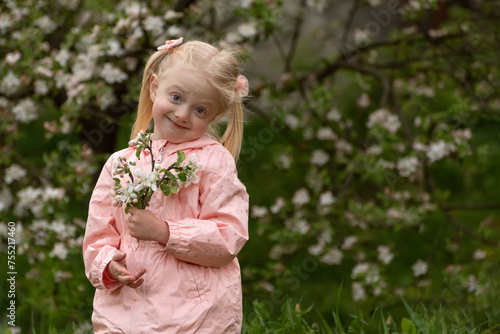 Spring blossom flowers for cute blonde child in flowering garden. Portrait of little child girl near blooming tree.