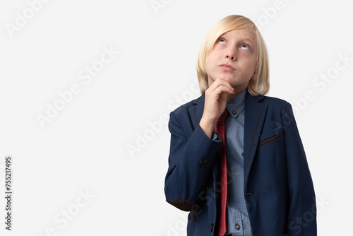 Thoughtful young man with short blond hair, dressed in blue jacket and red tie, looking up and thinking, isolated over white background.