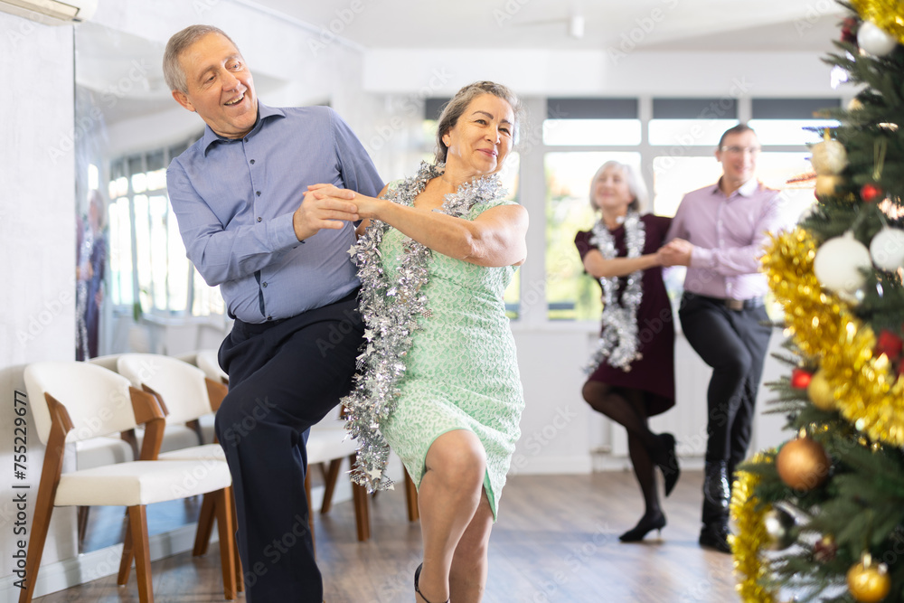Fototapeta premium Happy caucasian adult man and lady dancing rock and roll dance in modern dance studio during celebration Christmas and New Year