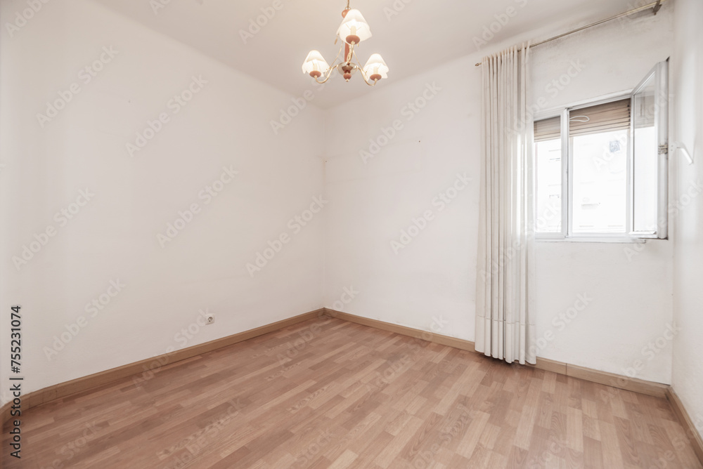 An empty room with light wooden floors and a three-tulip lamp on the ceiling. An empty room with light wooden floors and a three-tulip lamp on the ceiling.