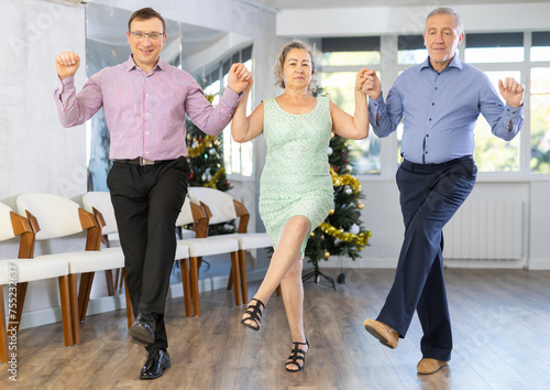 Group men and women dancing folk dance in row in studio.. photo