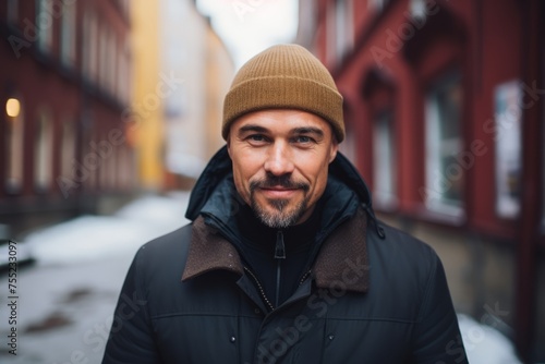 Portrait of a handsome middle-aged man in a hat and coat on the street.