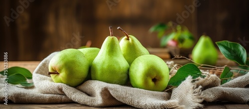 A group of fresh green pears displayed on a clothcovered wooden table, showcasing natural foods from a flowering plant, perfect as a staple food or ingredient for any event photo