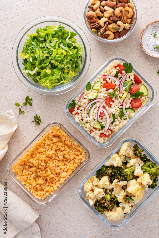 Healthy vegan meal prep with roasted vegetables, cooked lentils, couscous salad and nuts