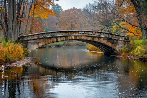 Scenic Autumn Bridge over Tranquil River Surrounded by Vibrant Fall Foliage in a Peaceful Forest