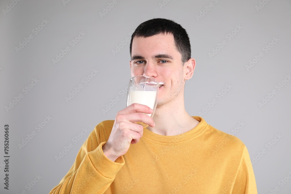Milk mustache left after dairy product. Man drinking milk on gray background Milk mustache left after dairy product. Man drinking milk on gray background