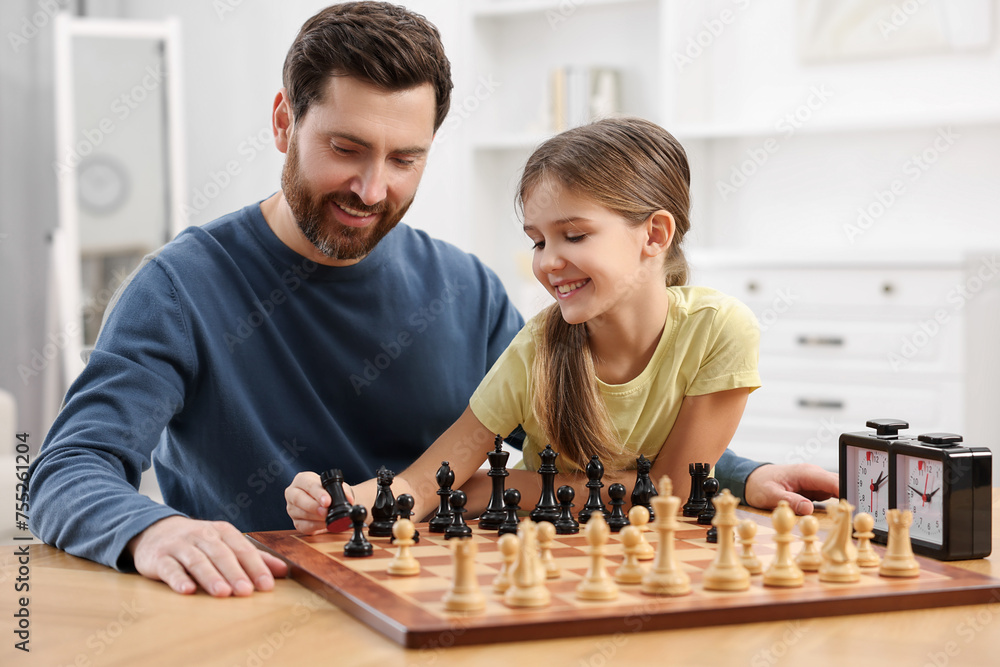 Father teaching his daughter to play chess at home Father teaching his daughter to play chess at home