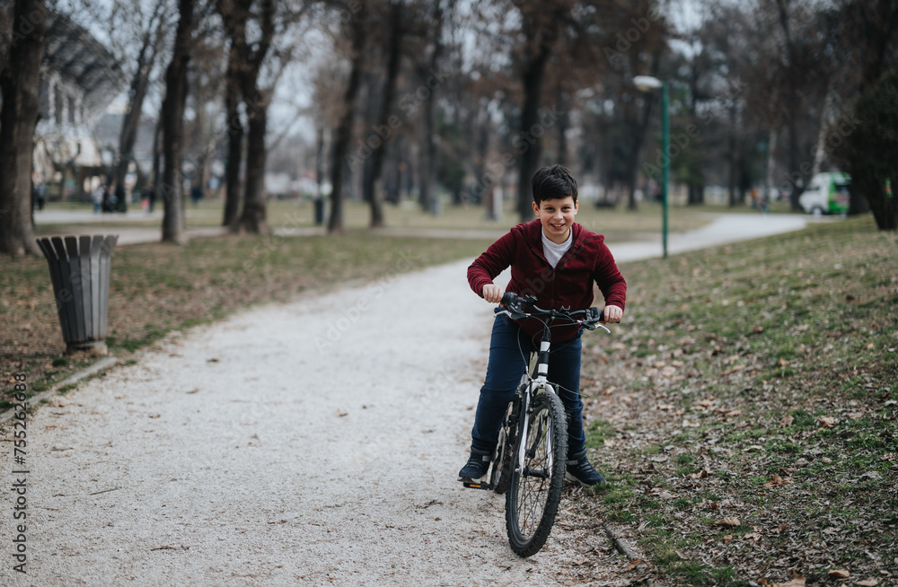 Smiling young boy on a bicycle enjoying his ride along a pathway in a lush city park, representing childhood joy and freedom.