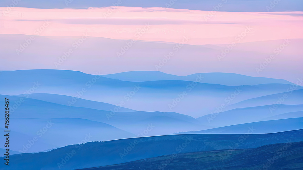 Layers of blue mountains and hills shrouded in mist under a soft pink and blue gradient sky at twilight