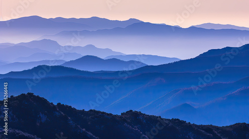 Layers of mountain ridges under a gradient twilight sky showcasing shades of blue purple and a hint of orange