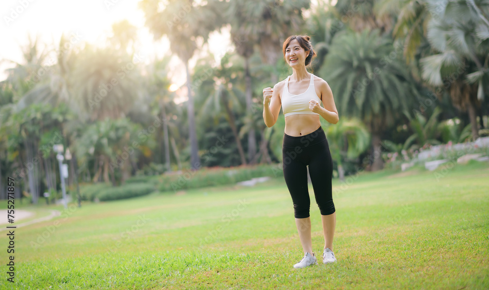 Happy fitness woman achieve goal, finish marathon with hands up, celebrating victory while jogging, triumphing in park