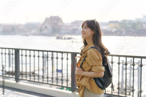 young Asian woman in 30s on a solo adventure. Technology in hand, she captures the essence of cultural exploration and joyful discovery.