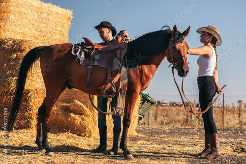 Friends saddling a horse in an equestrian center