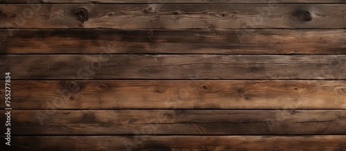 A closeup of a brown hardwood plank wall with a blurred background. The wood stain enhances the natural beige pattern of the building material