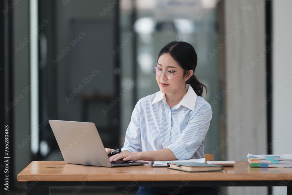 Young smart Asian businesswoman working with laptop in her office room. Young smart Asian businesswoman working with laptop in her office room.