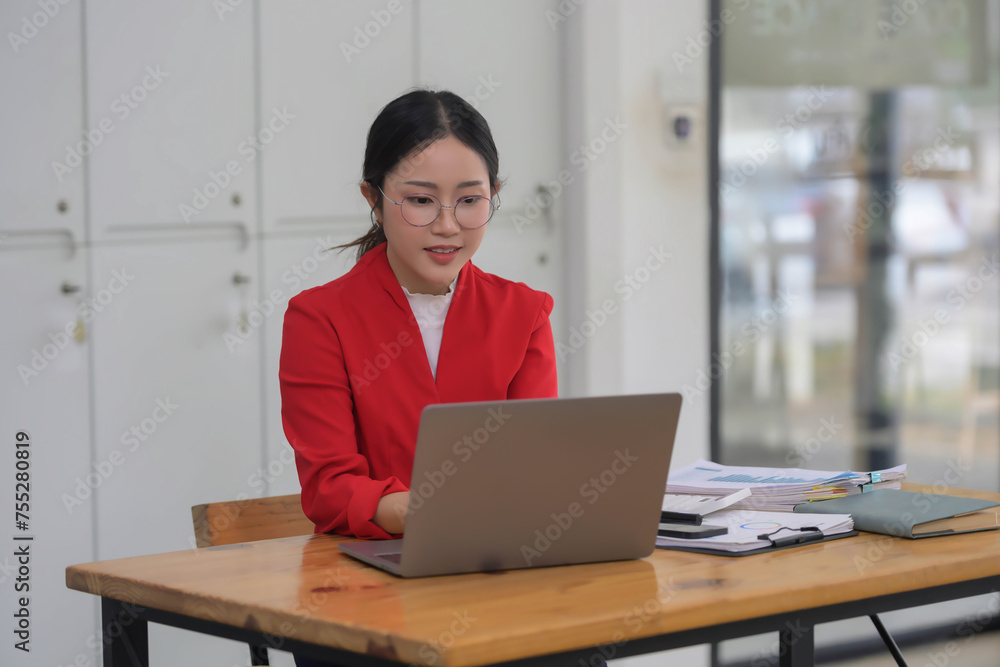 Beautiful young concentrated business woman wearing red blazer working in her office room. Beautiful young concentrated business woman wearing red blazer working in her office room.
