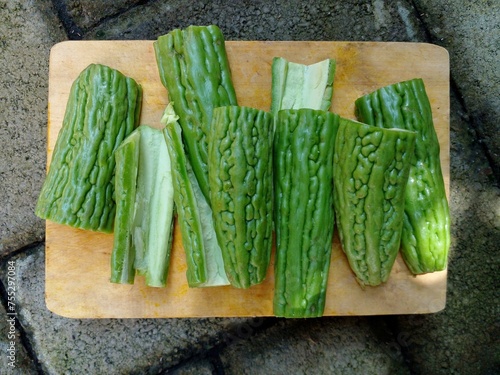 The bitter melon or bitter gourd that has been cleaned and cut is placed on a wooden cutting board.