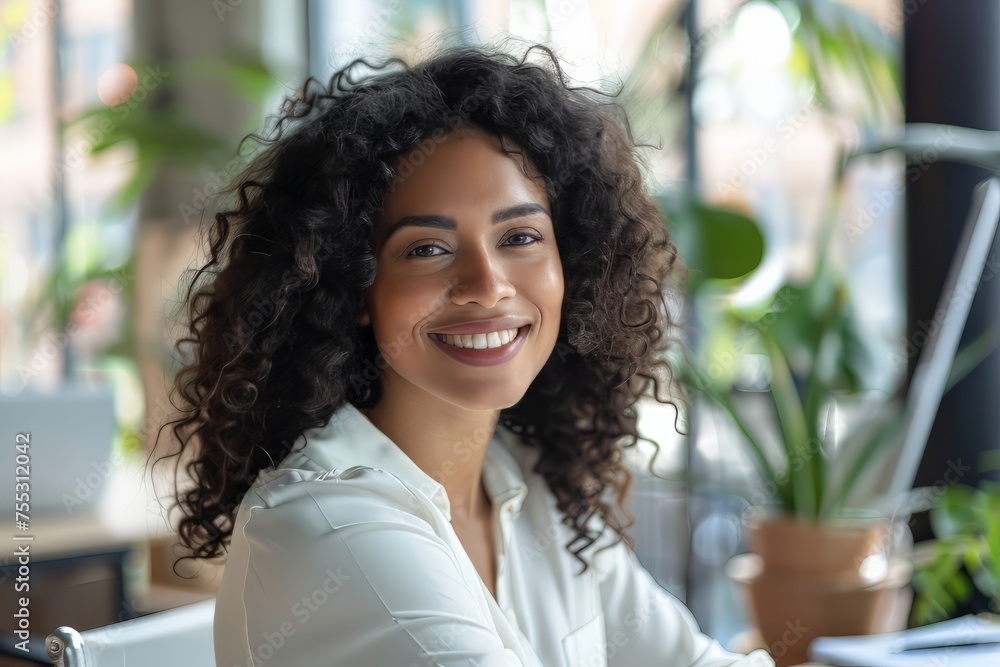 Smiling woman sitting at her desk in office. Happy business woman sitting in office Smiling woman sitting at her desk in office. Happy business woman sitting in office