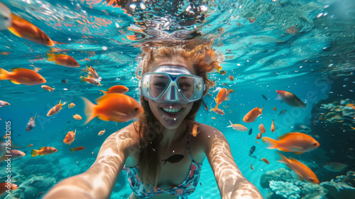 An underwater selfie of a smiling woman snorkeling surrounded by colorful tropical fish in a clear blue ocean. © AI Art Factory