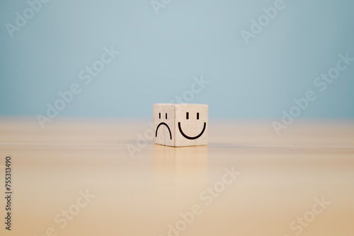 Emotional state and mental health concept, Smile face on bright side and sad face on dark side of wooden block cube for positive mindset selection. photo