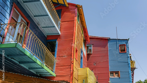 The houses with bright multicolored fluted walls are built in the La Boca quarter of Buenos Aires. Windows and balconies on the facade. The blue sky. Argentina.