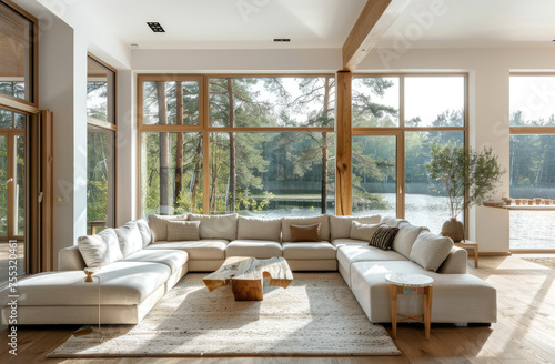 White modern living room with large windows and a view of a forest lake, beige sofa