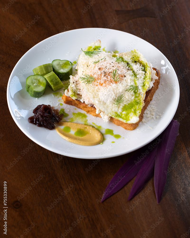 Avocado Egg Toast with Sauce, Garnished with Fresh Herbs and Served with Cucumber Slices and Mustard. Avocado Egg Toast with Sauce, Garnished with Fresh Herbs and Served with Cucumber Slices and Mustard.