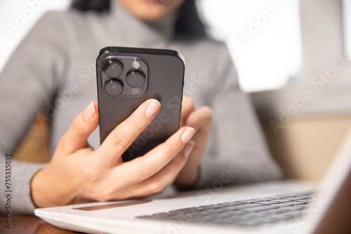 woman hand smart phone with computer on office