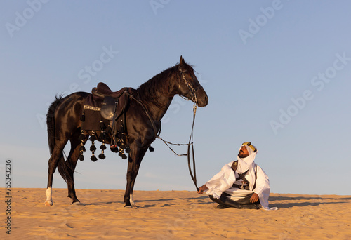 Saudi man in a desert with his horse and dogs © katiekk2