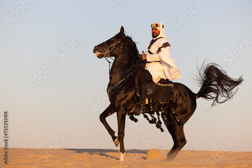 Saudi man in a desert with his black stallion © katiekk2
