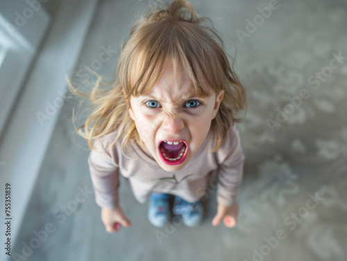 Upset child having a temper tantrum looking up at camera while angrily screaming