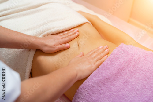 Top view of hands massaging female abdomen.Therapist applying pressure on belly. Woman receiving massage at spa salon
