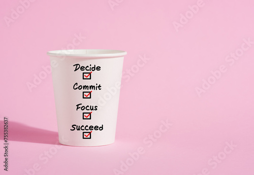 Decide, commit, focus and succeed on a paper coffee cup on pink background.