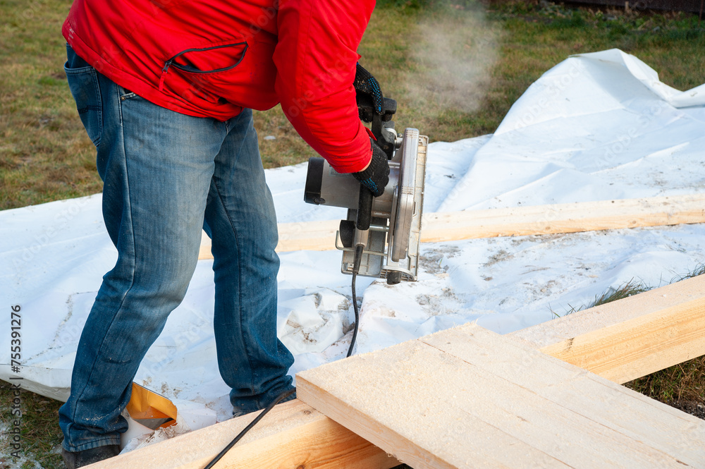 A man in a red jacket is engaged in construction using wooden planks