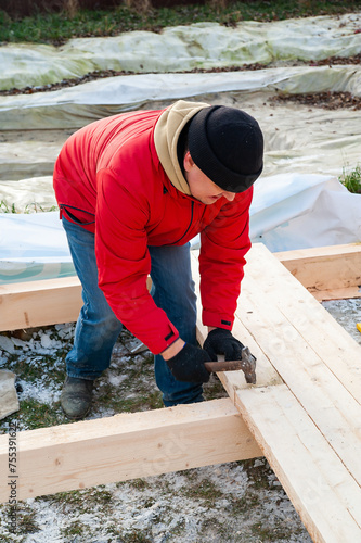 Wallpaper Mural A man in a red jacket is engaged in construction using wooden planks Torontodigital.ca