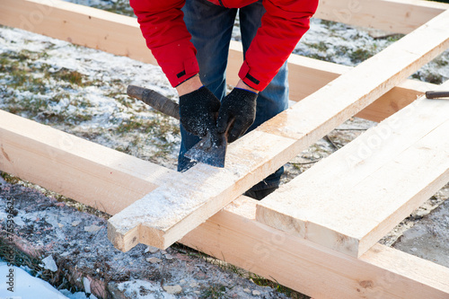 A man in a red jacket is engaged in construction using wooden planks