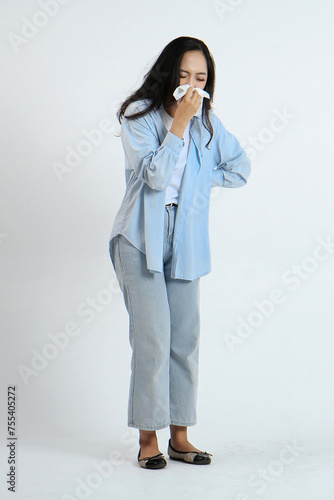 backview full leght shoot of asian Indonesian woman wearing casual attire have a fever, flu, hand in use tissues paper sneezing nose, runny and cough, standing on isolated background. photo
