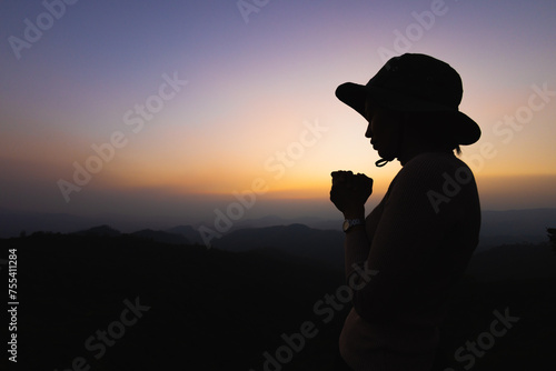 Silhouette of a women is praying to God on the mountain. Praying hands with faith in religion and belief in God on blessing background. Power of hope or love and devotion.