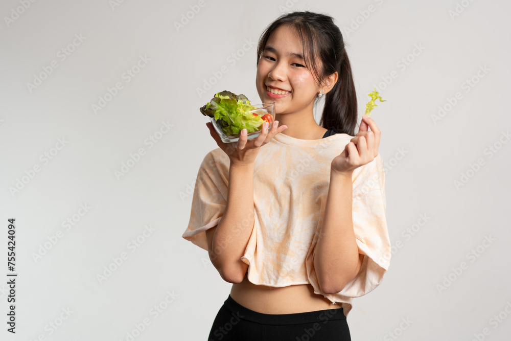 Portrait of a happy playful Asian girl eating fresh salad from a glass bowl after workout at home. Young lady Enjoying Healthy Nutrition And Organic Food, Having Vegetarian Meal Portrait of a happy playful Asian girl eating fresh salad from a glass bowl after workout at home. Young lady Enjoying Healthy Nutrition And Organic Food, Having Vegetarian Meal