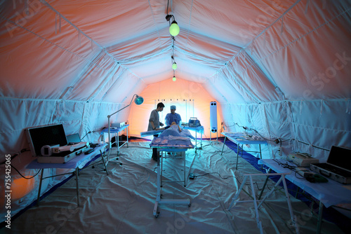 Medical worker and a student near the lying dummy inside the tent in a field hospital