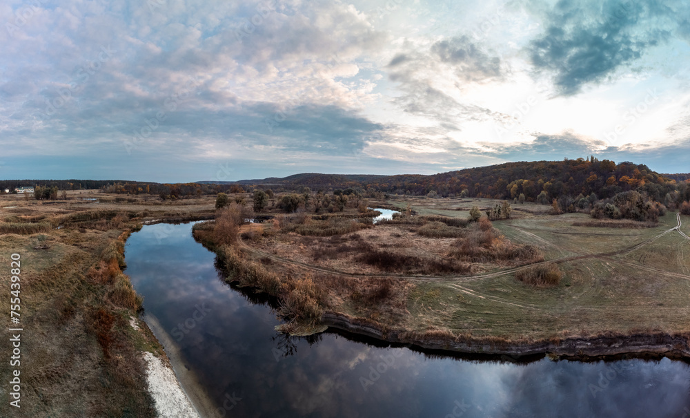 Aerial panorama of river in autumn with mirror calm water and epic cloudy sky