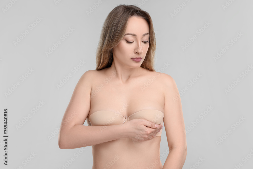 Mammology. Young woman doing breast self-examination on light grey background Mammology. Young woman doing breast self-examination on light grey background