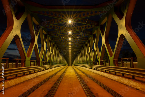 A long exposure of a pedestrian bridge over a river at night. The old bridge. Bratislava, Slovakia. Perspective view.